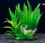 Artificial green fern plant with small flowers on a dark background