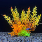 Artificial aquarium plants with orange, green, and red hues on a dark background